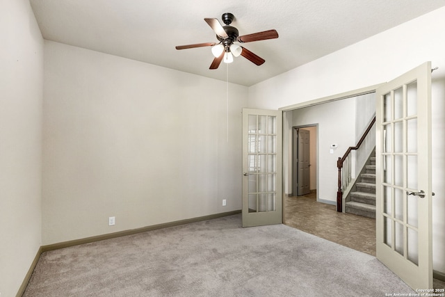 carpeted spare room featuring ceiling fan, stairs, baseboards, and french doors