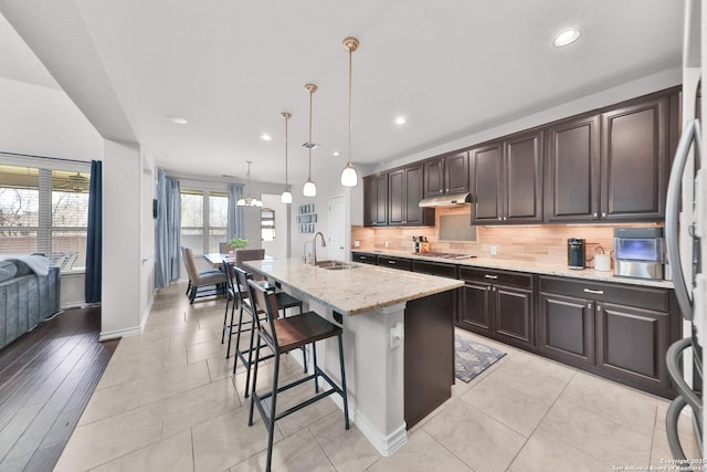 kitchen featuring tasteful backsplash, a sink, light stone counters, and dark brown cabinetry