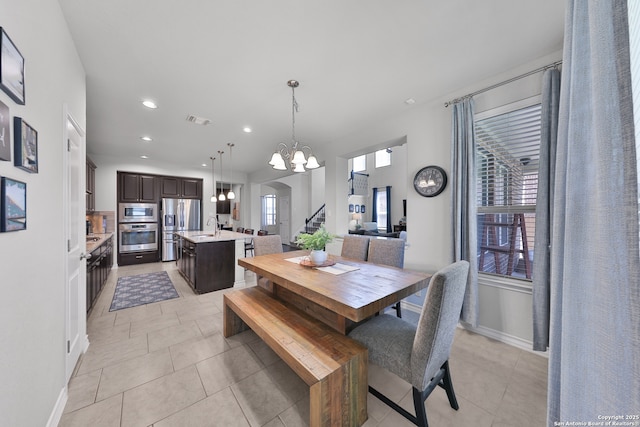 dining room featuring stairs, visible vents, a notable chandelier, and light tile patterned flooring