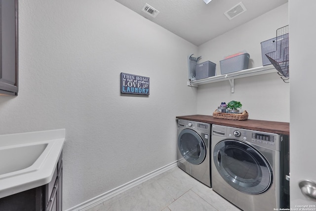 washroom with a sink, washing machine and dryer, visible vents, and baseboards