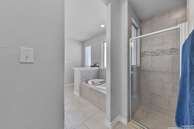 bathroom with tile patterned flooring, a garden tub, a shower stall, and baseboards