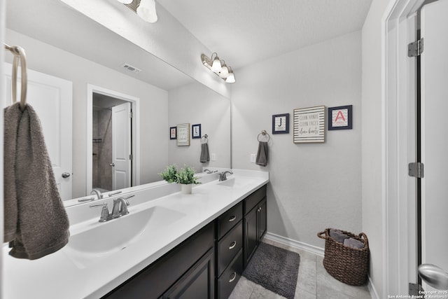 bathroom with double vanity, a sink, visible vents, and baseboards