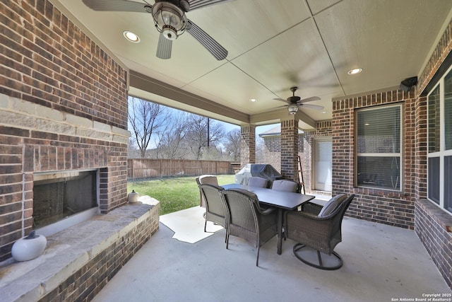 view of patio / terrace featuring ceiling fan, an outdoor brick fireplace, fence, and outdoor dining area