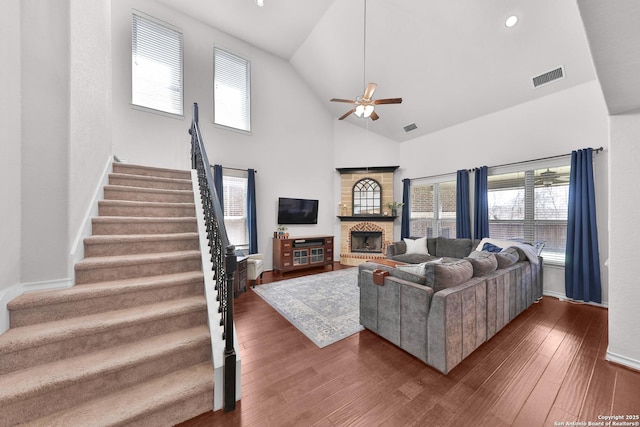 living area featuring a wealth of natural light, a brick fireplace, visible vents, and dark wood finished floors