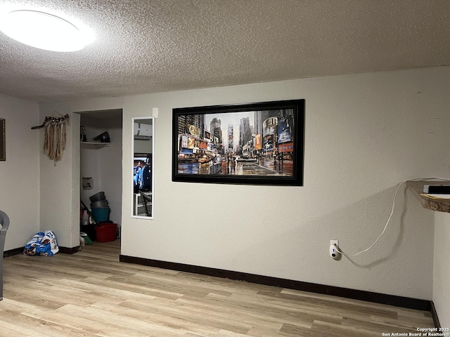 empty room featuring a textured ceiling, baseboards, and light wood-style floors