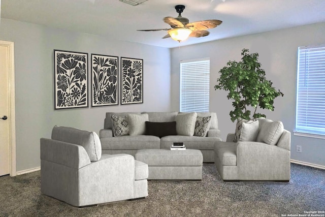 living area with a ceiling fan, dark carpet, and baseboards