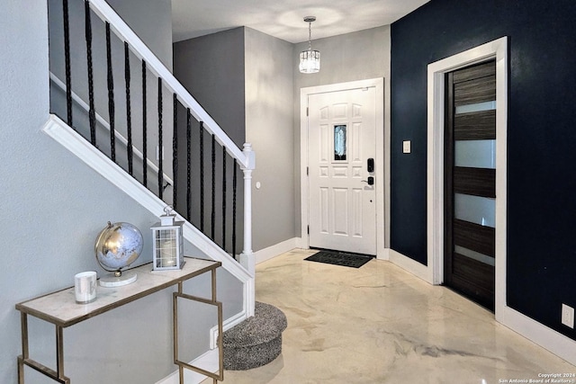 entrance foyer featuring stairway, baseboards, and finished concrete flooring