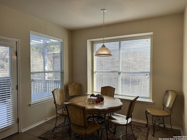 tiled dining room featuring baseboards and a textured ceiling