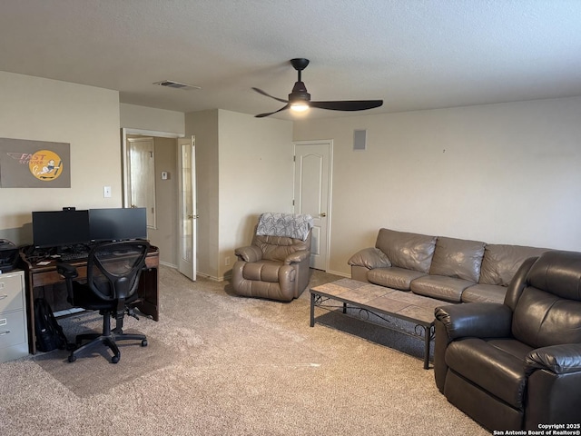 living room featuring visible vents, light carpet, and a textured ceiling