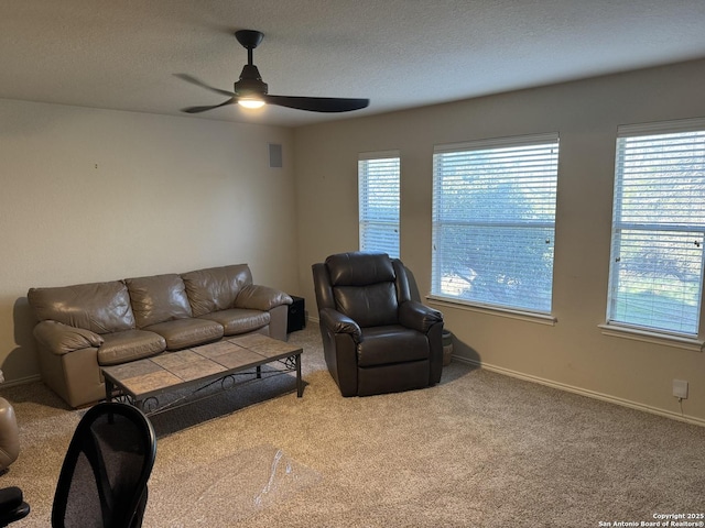 carpeted living room featuring a ceiling fan, baseboards, and a textured ceiling