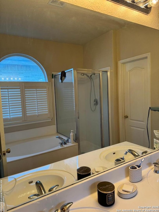 bathroom with visible vents, a stall shower, vanity, and a bath