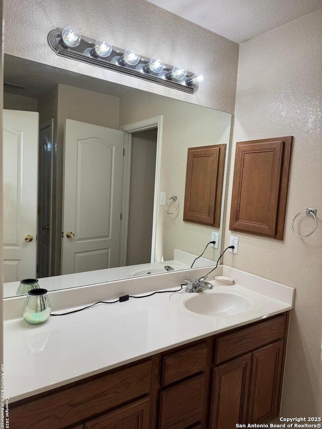 bathroom with a textured wall and vanity