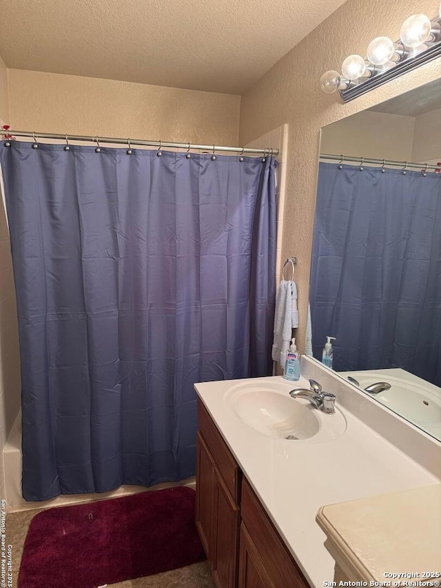 full bathroom featuring a shower with curtain, a textured wall, vanity, and a textured ceiling