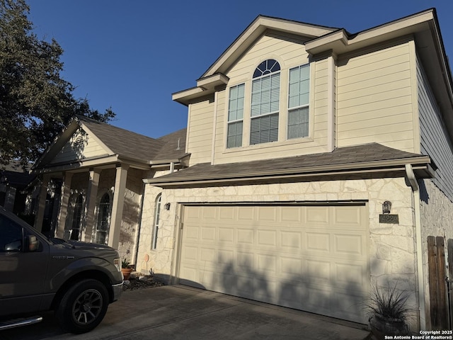 view of front of property featuring a garage, stone siding, and driveway