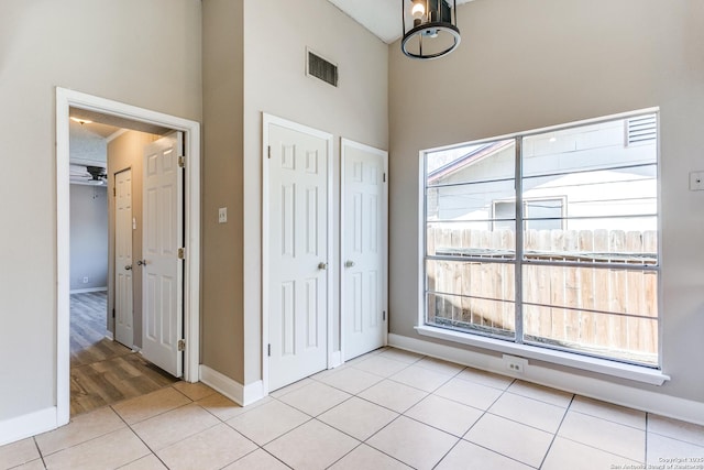 unfurnished bedroom featuring light tile patterned floors, multiple windows, visible vents, and baseboards