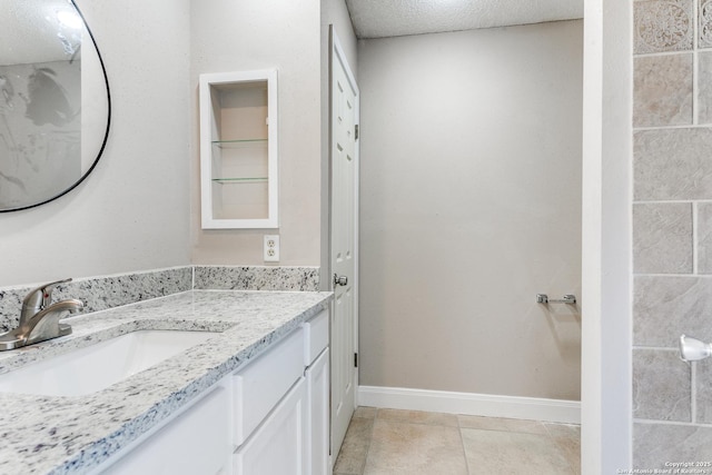 bathroom with tile patterned flooring, baseboards, a textured ceiling, and vanity