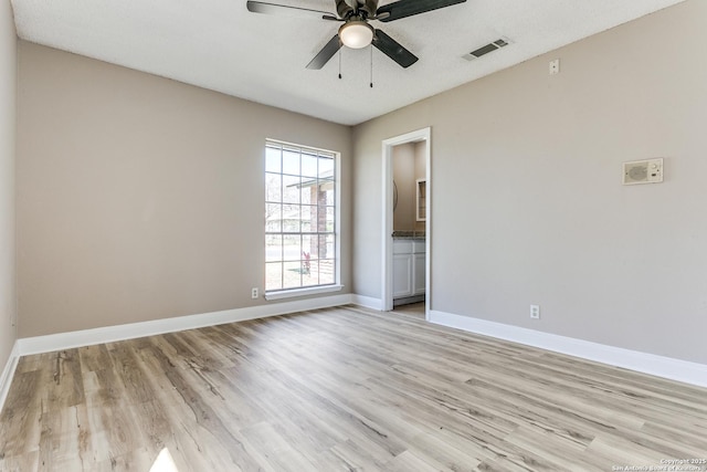 empty room featuring ceiling fan, light wood-style floors, visible vents, and baseboards