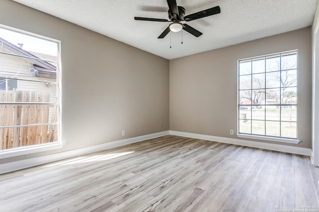 spare room with a textured ceiling, wood finished floors, a ceiling fan, and baseboards