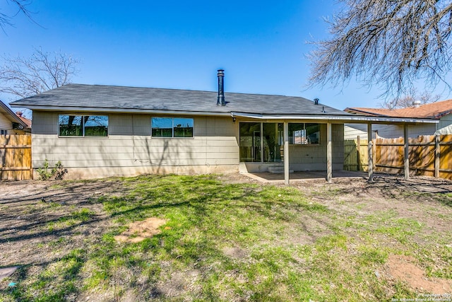 back of property with a fenced backyard and a lawn