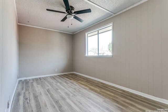 empty room featuring baseboards, a ceiling fan, ornamental molding, wood finished floors, and a textured ceiling