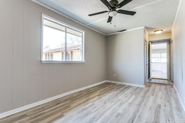 spare room with light wood-style floors, plenty of natural light, visible vents, and a textured ceiling