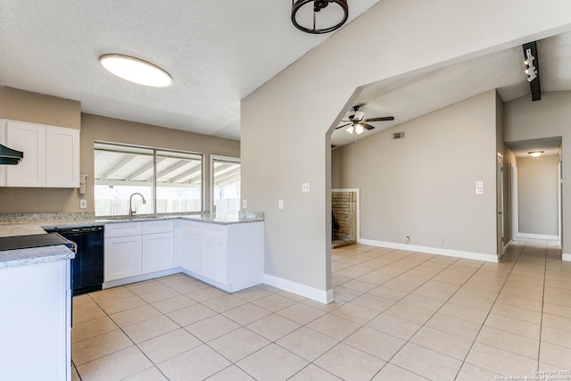 kitchen featuring light tile patterned floors, lofted ceiling, white cabinets, a sink, and dishwasher