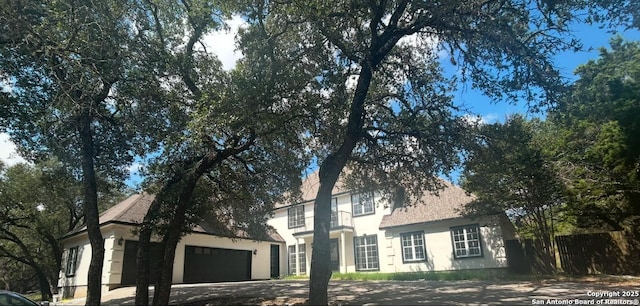 view of front of property with a garage, driveway, fence, and stucco siding