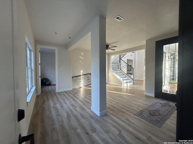 entryway with stairway, wood finished floors, visible vents, and baseboards