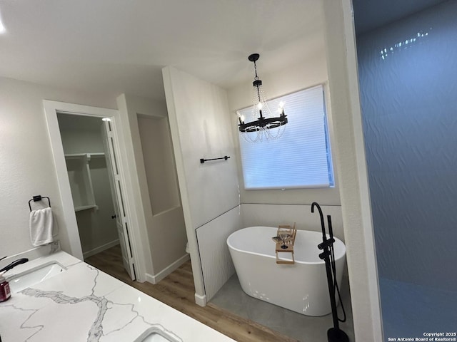 bathroom featuring a freestanding bath, a sink, wood finished floors, and a chandelier