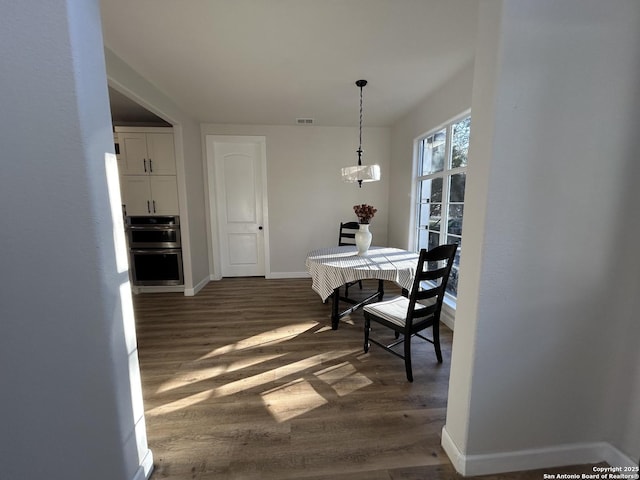 dining area featuring dark wood-style flooring, visible vents, and baseboards