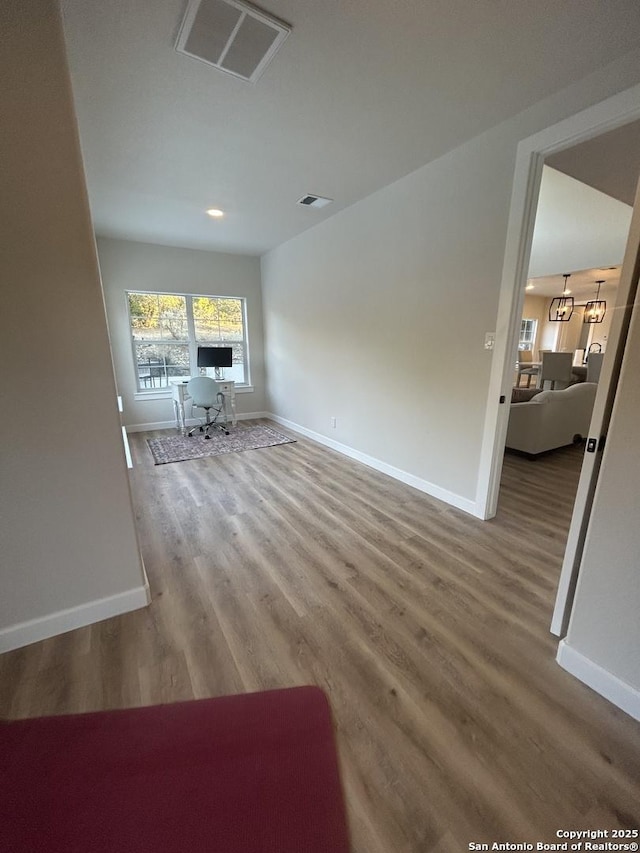 unfurnished living room with baseboards, visible vents, and wood finished floors