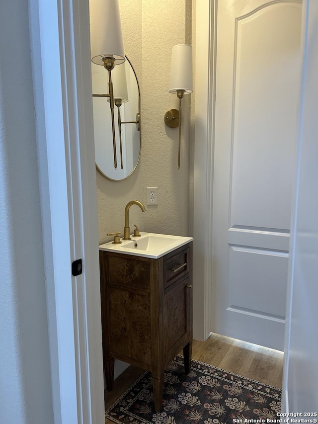 bathroom with a textured wall, wood finished floors, and vanity