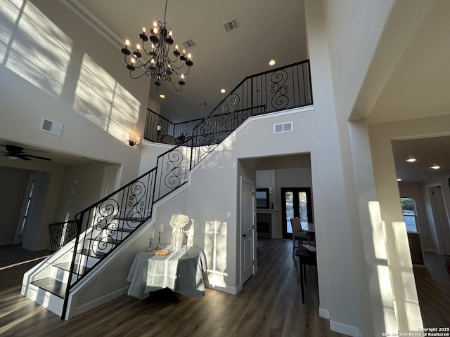 stairs featuring a towering ceiling, wood finished floors, and visible vents