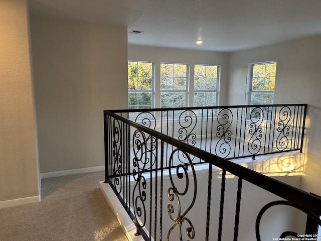 hall featuring carpet flooring, visible vents, and baseboards