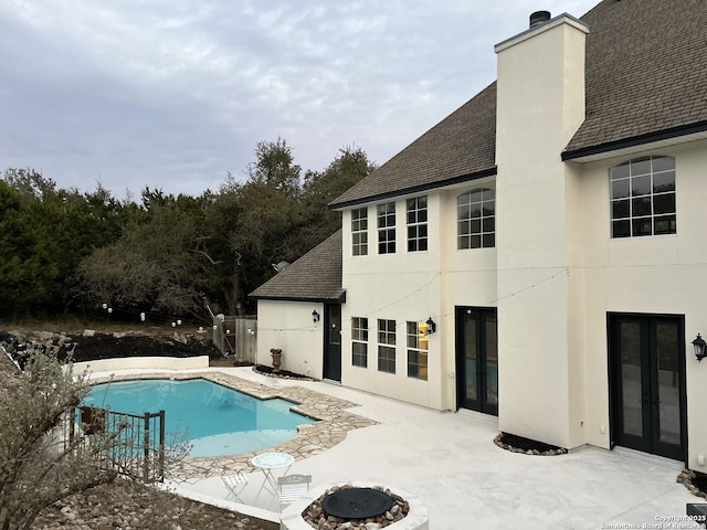 outdoor pool with french doors and a patio