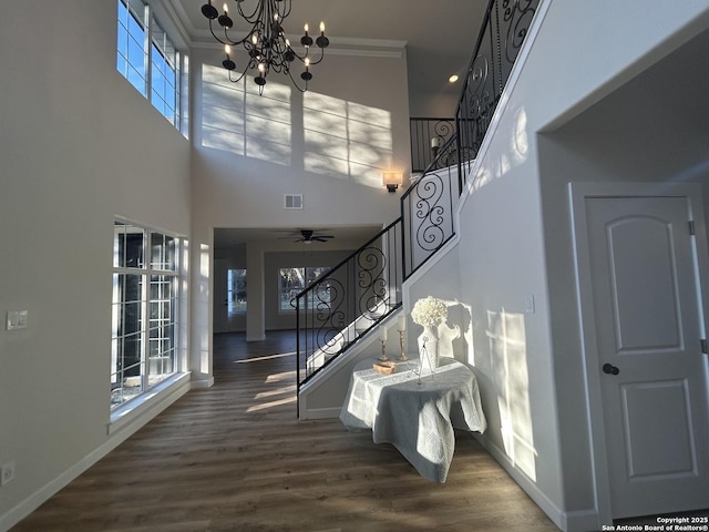 staircase featuring wood finished floors, visible vents, baseboards, ornamental molding, and an inviting chandelier