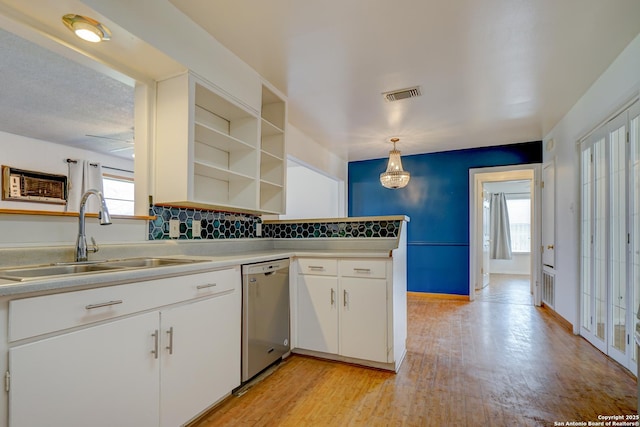 kitchen featuring visible vents, light wood-type flooring, stainless steel dishwasher, open shelves, and a sink