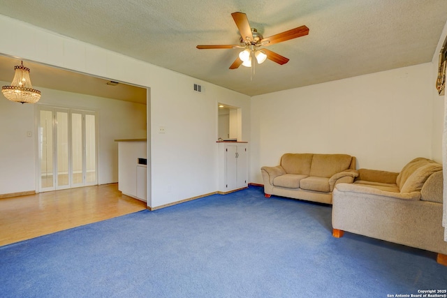 carpeted living room with a textured ceiling, ceiling fan, visible vents, and baseboards