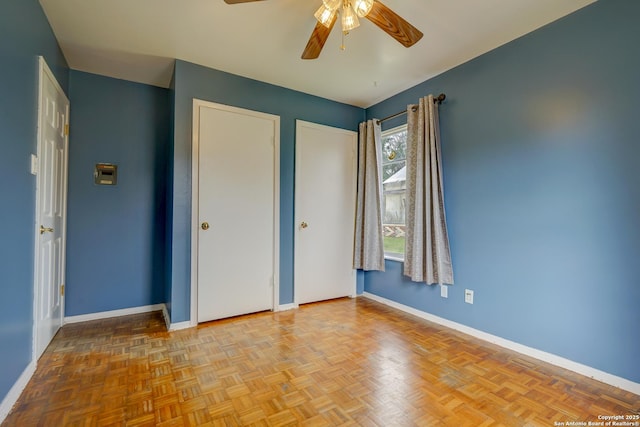 unfurnished bedroom featuring two closets, baseboards, and a ceiling fan