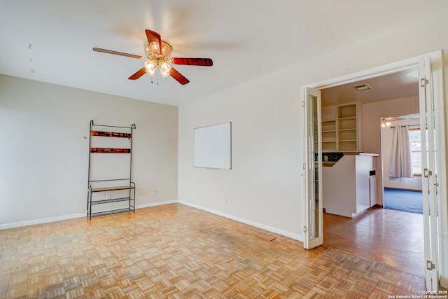 spare room with ceiling fan, parquet flooring, visible vents, and baseboards