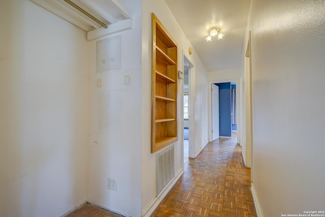 corridor featuring built in shelves, visible vents, and baseboards