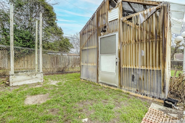 view of greenhouse with fence and a lawn