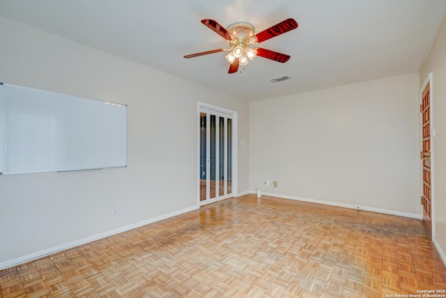 empty room featuring ceiling fan, visible vents, and baseboards