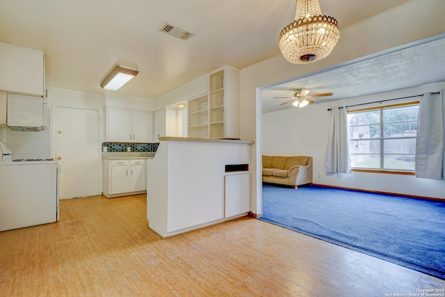 kitchen with light wood-style flooring, range, washer / dryer, and white cabinets