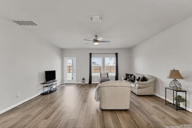 living room with baseboards, visible vents, and wood finished floors