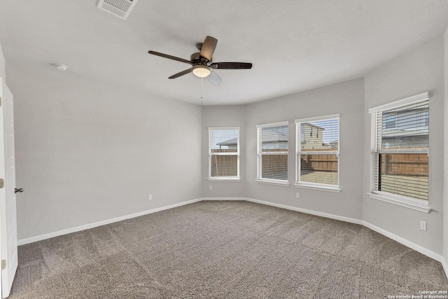 carpeted spare room featuring ceiling fan, visible vents, and baseboards