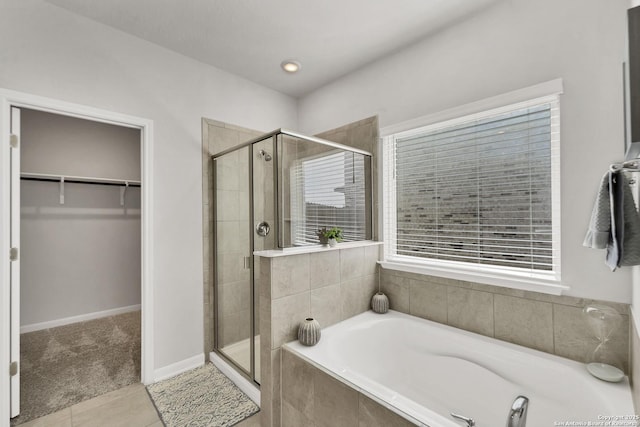 full bath with a bath, a shower stall, a walk in closet, and tile patterned floors