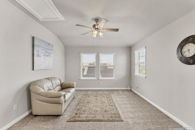 living area with attic access, baseboards, ceiling fan, and carpet flooring