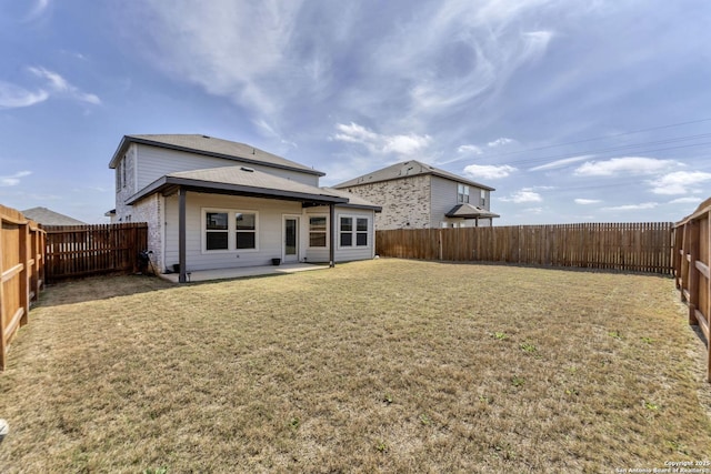 rear view of house featuring a fenced backyard, a yard, and a patio