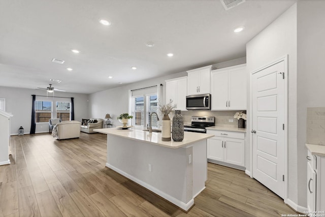 kitchen featuring visible vents, decorative backsplash, appliances with stainless steel finishes, a sink, and light wood-type flooring